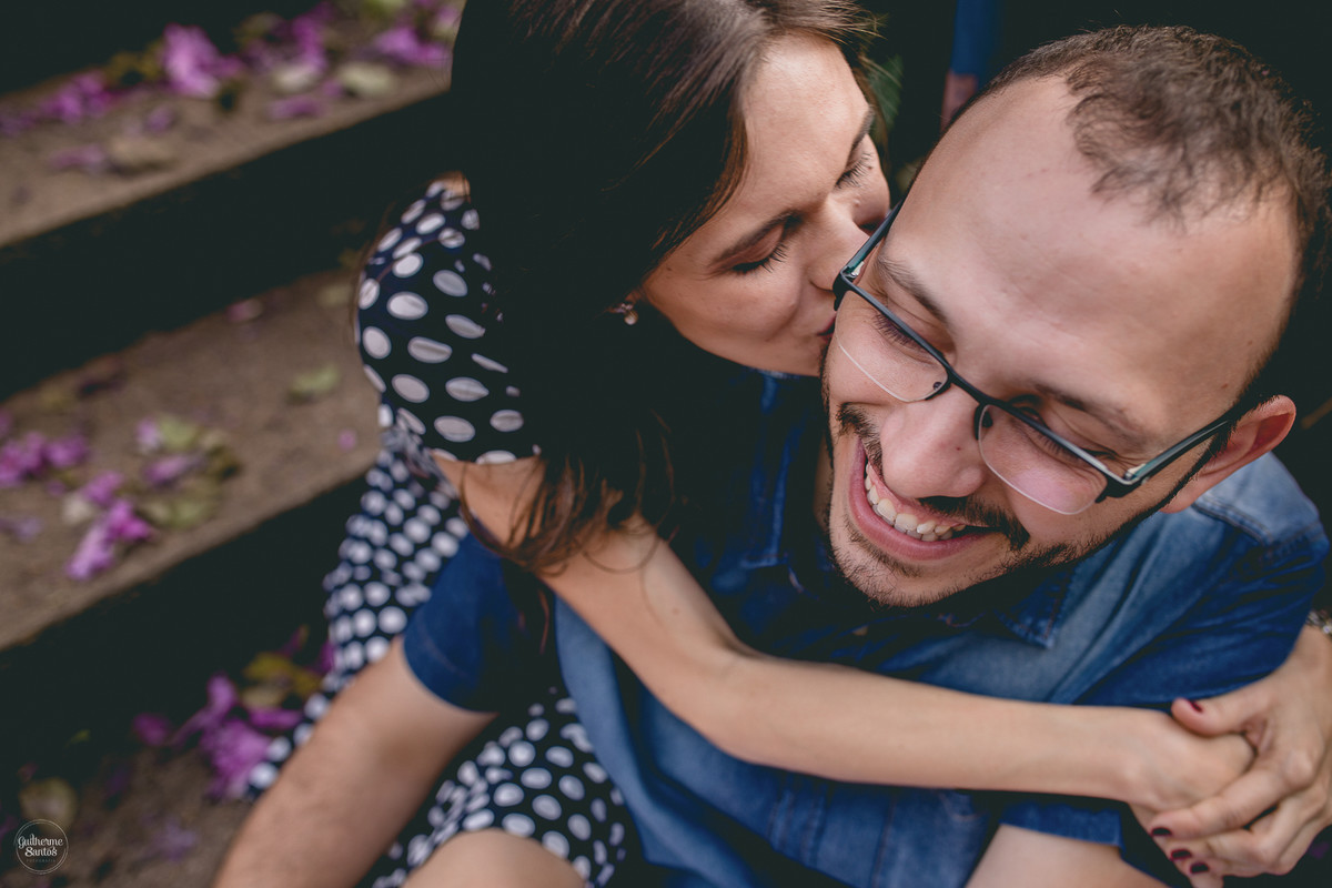 Fotografia de pré casamento feita pelo fotógrafo Guilherme Santos, casal de noivos se abraçando, noiva beijando o rosto do noivo, noivo sorrindo durante a sessão de fotos na USP em São Carlos.
