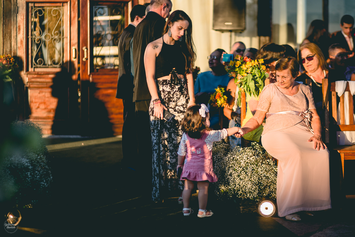 Fotografia de casamento feita pelo fotógrafo Guilherme Santos, criança cumprimentando uma senhora momentos antes da cerimônia ao ar livre em Bauru,