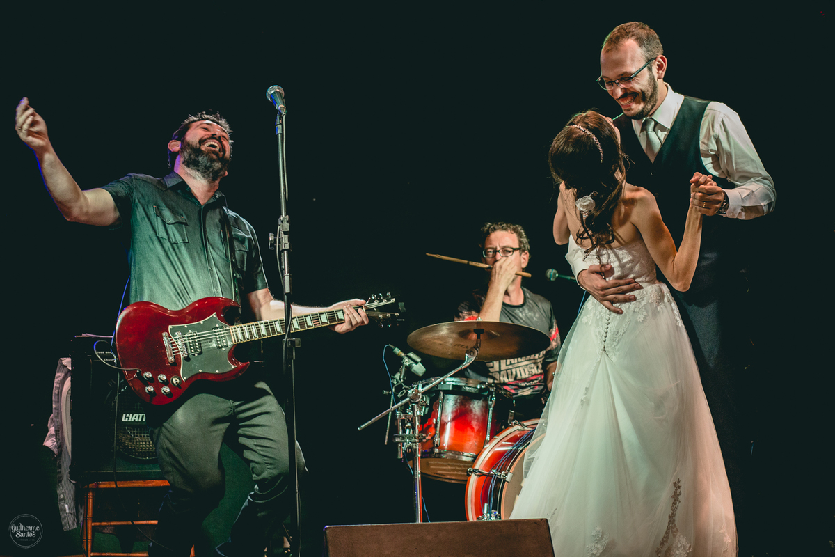 Fotografia de casamento feita pelo fotógrafo Guilherme Santos, casal de noivos dançando em cima do palco enquanto a banda de música está tocando na festa de casamento em Jaú.
