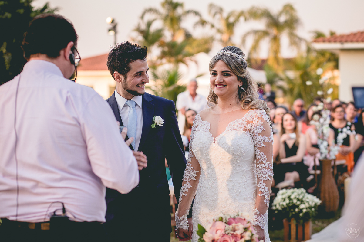 Fotografia de casamento pelo fotógrafo Guilherme Santos, noivo sorrindo olhando a noiva sorrindo durante a cerimônia de casamento ao ar livre em Pederneiras.