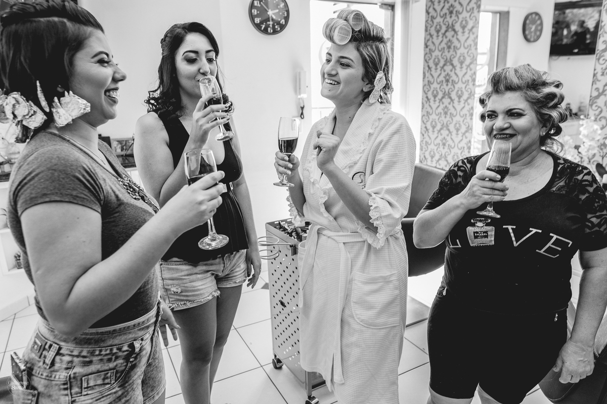 Fotografia de casamento pelo fotógrafo Guilherme Santos, noiva bebendo champagne com a mãe e madrinhas. Brinde das madrinhas durante os preparativos do casamento.