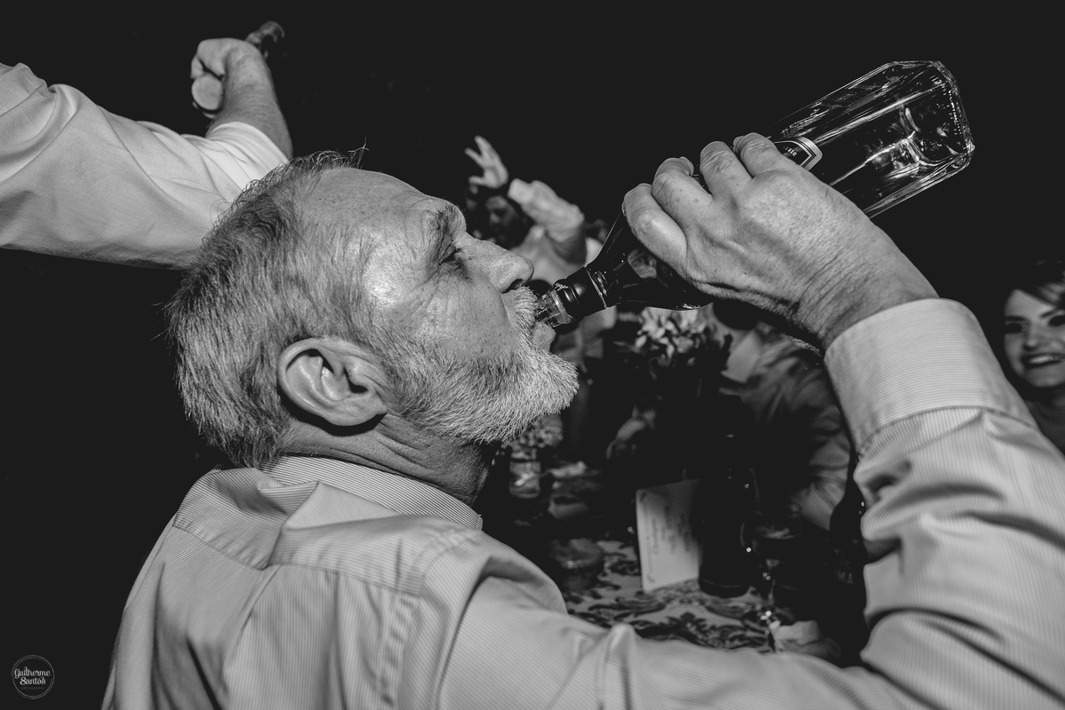 Fotografia de casamento pelo fotógrafo Guilherme Santos, convidado bebendo durante a festa de casamento.