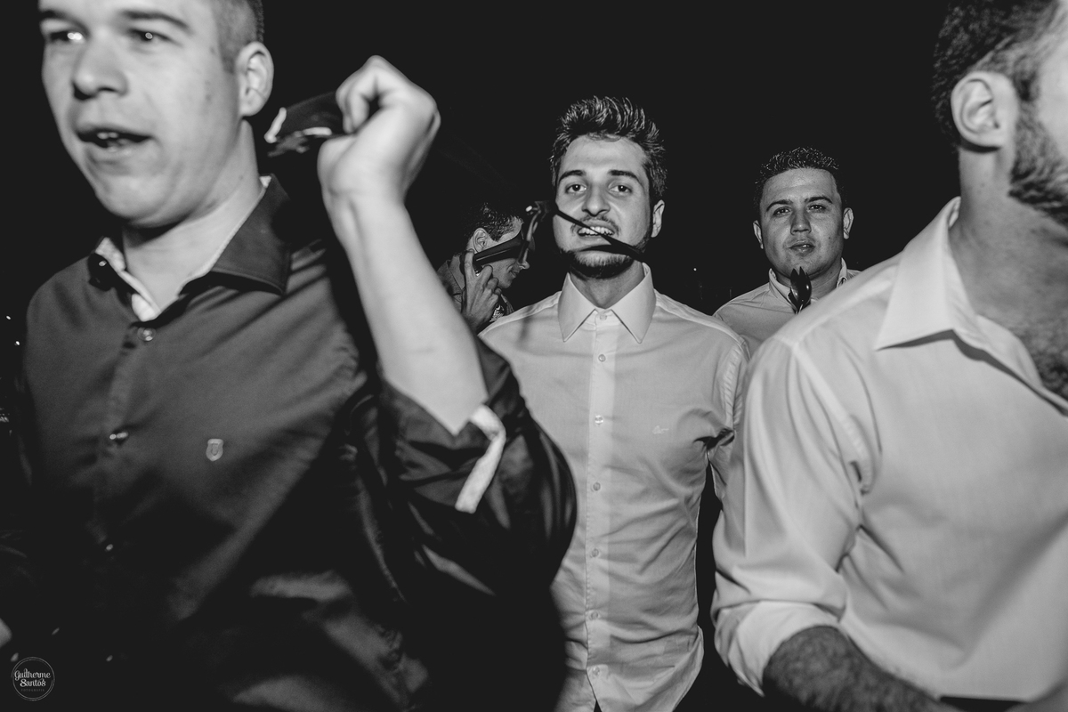 Fotografia de casamento pelo fotógrafo Guilherme Santos, noivo no momento da gravata com seus padrinhos na festa de casamento.