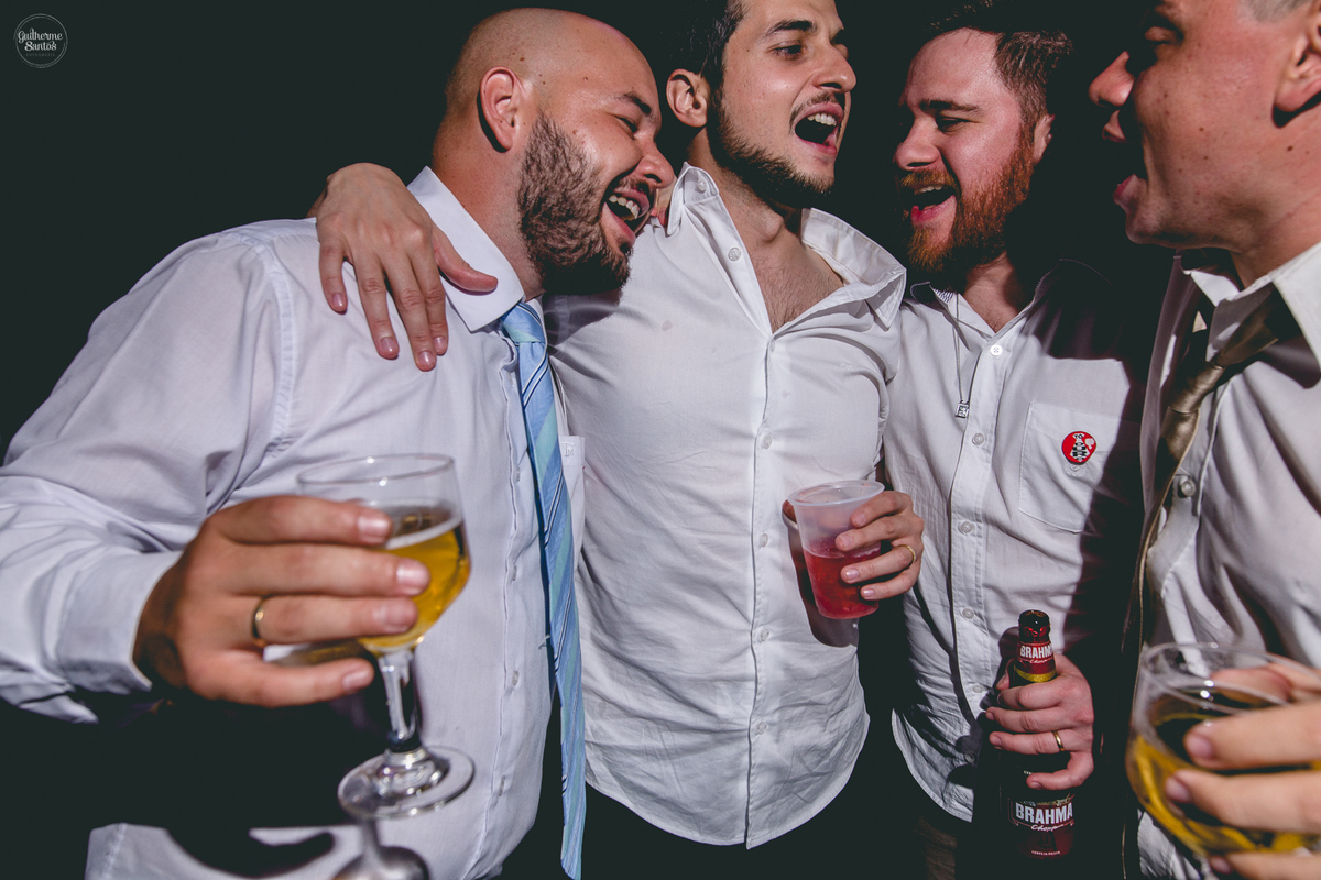 Fotografia de casamento pelo fotógrafo Guilherme Santos, noivo cantando com os convidados durante a festa de casamento ao ar livre.