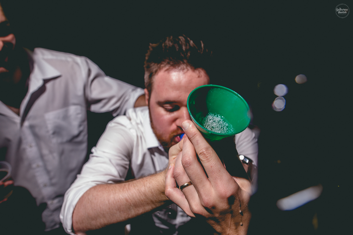 Fotografia de casamento pelo fotógrafo Guilherme Santos, convidado bebendo durante a festa de casamento ao ar livre.