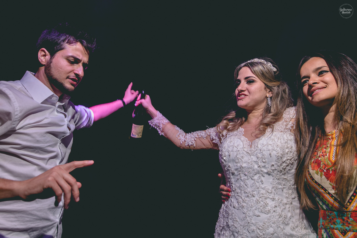 Fotografia de casamento pelo fotógrafo Guilherme Santos, noiva dançando com o noivo e com a madrinha durante a festa de casamento.