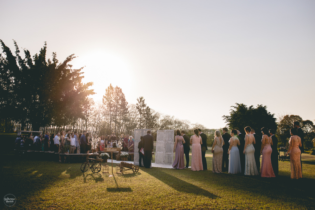 Fotografia de casamento pelo fotógrafo Guilherme Santos,  madrinhas e padrinhos entrando no casamento ao ar livre em Pederneiras. Casamento com pôr do sol.