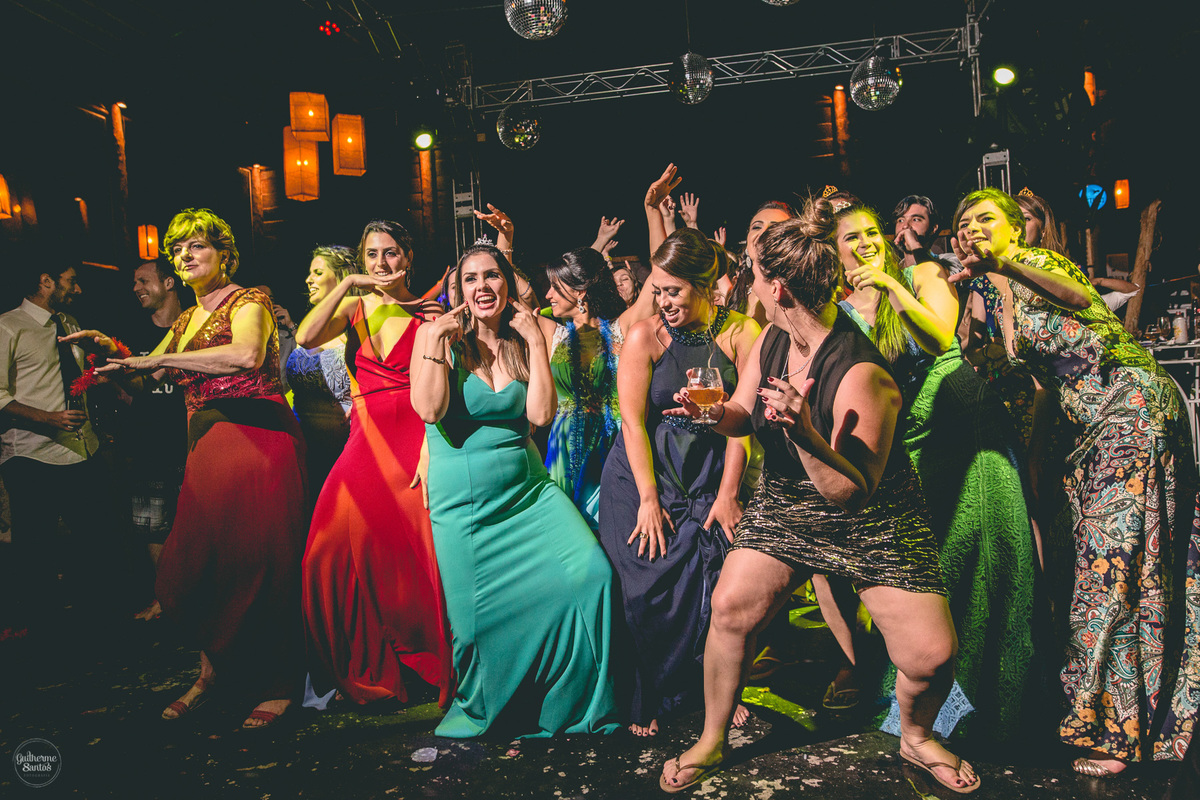 Fotografia de casamento pelo fotógrafo Guilherme Santos, convidadas dançando. Noiva jogando o buquê de flores durante a festa de casamento em Botucatu.
