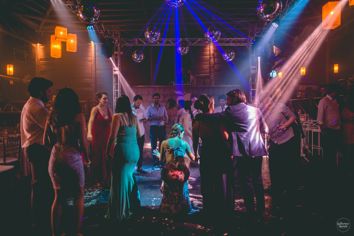 Fotografia de casamento pelo fotógrafo Guilherme Santos, convidados dançando na festa de casamento em Botucatu. Luzes lindas na festa de casamento.