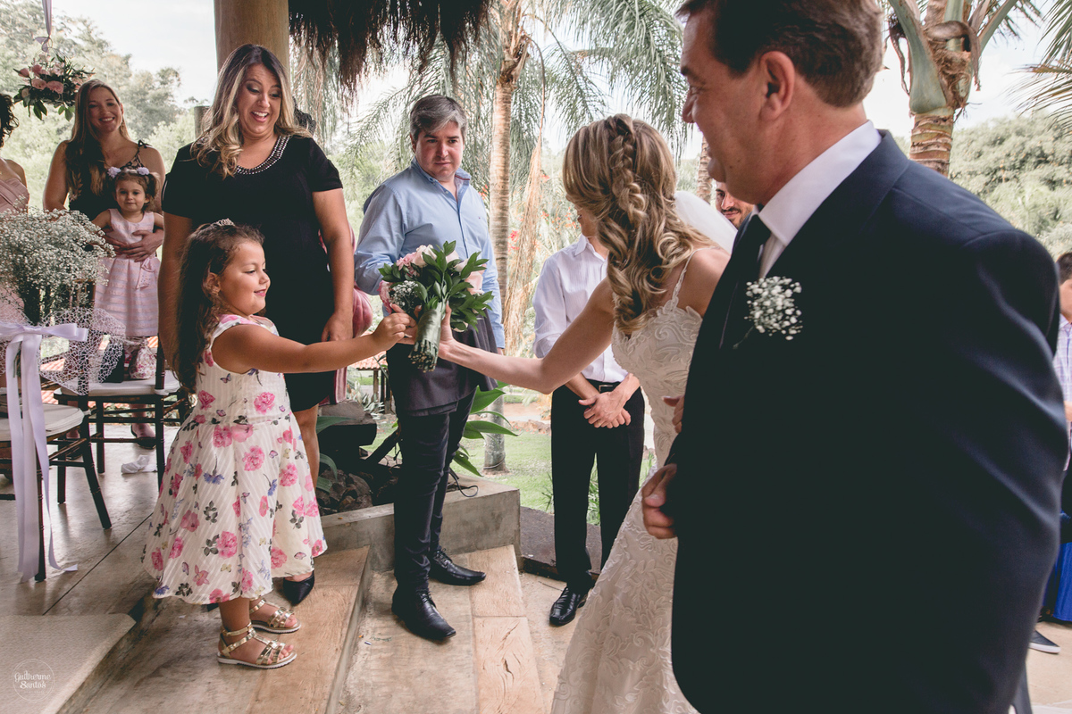 Fotografia de casamento feita no final de tarde pelo fotógrafo Guilherme Santos, noiva segurando flores em sua entrada no casamento ao ar livre em Botucatu.