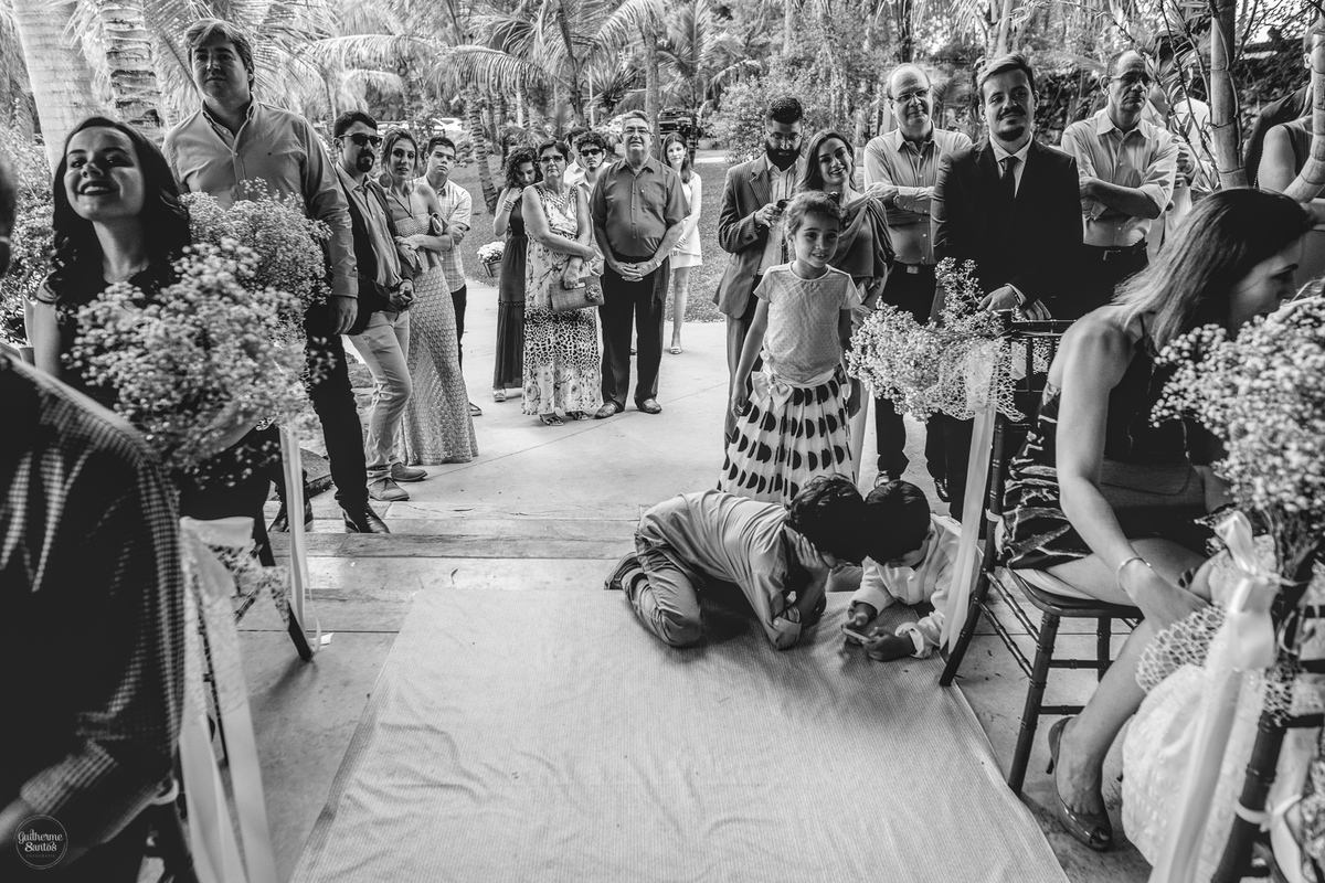 Fotografia de casamento feita no final de tarde pelo fotógrafo Guilherme Santos, convidados olhando os noivos durante a cerimônia de casamento ao ar livre em Botucatu. Crianças brincando durante o casamento.