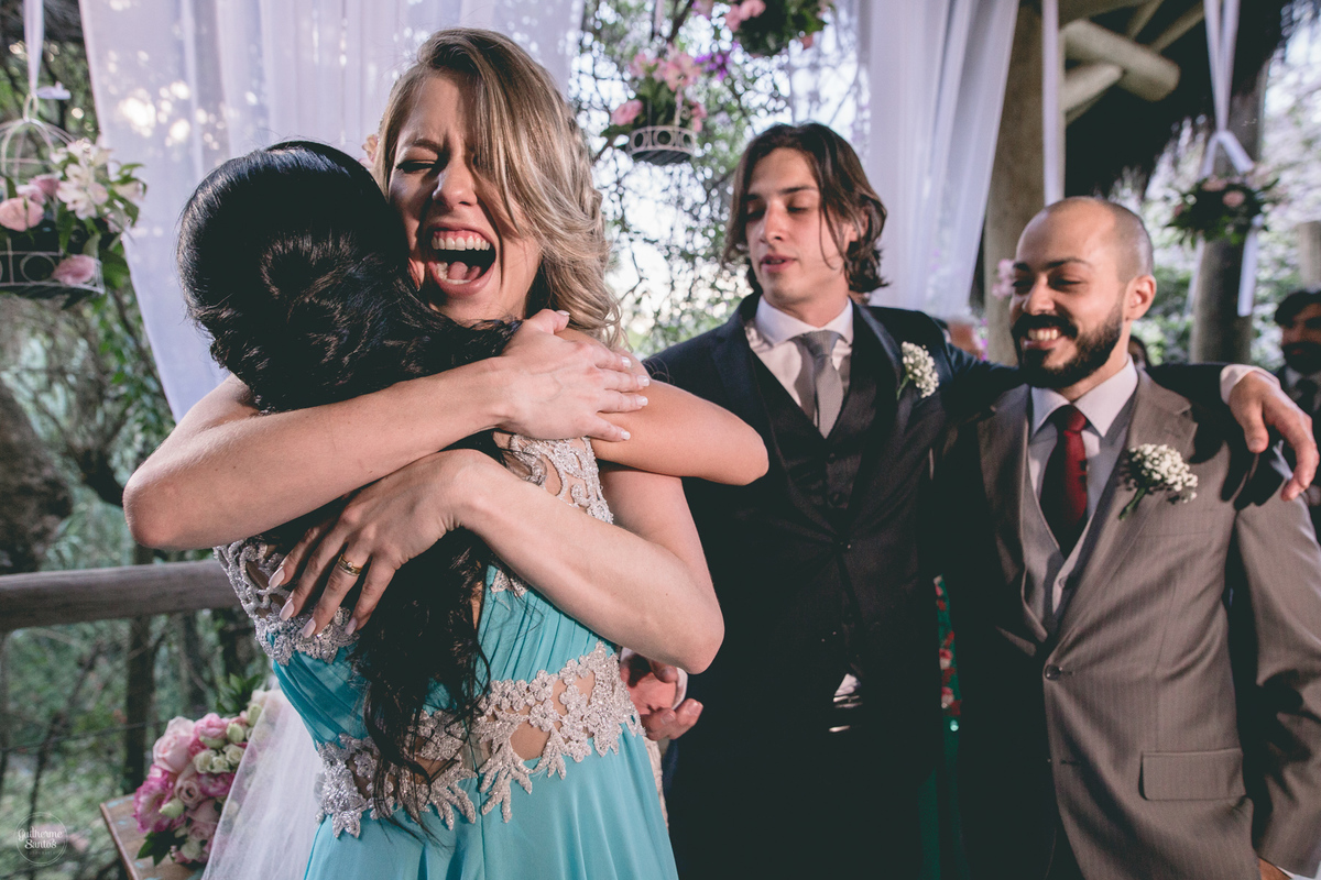 Fotografia de casamento feita no final de tarde pelo fotógrafo Guilherme Santos, noiva feliz abraçando a madrinha no casamento ao ar livre em Botucatu.
