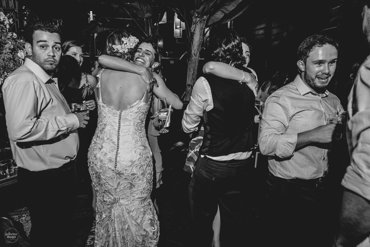 Fotografia de casamento pelo fotógrafo Guilherme Santos, noivos abraçando os convidados durante a festa de casamento animada.