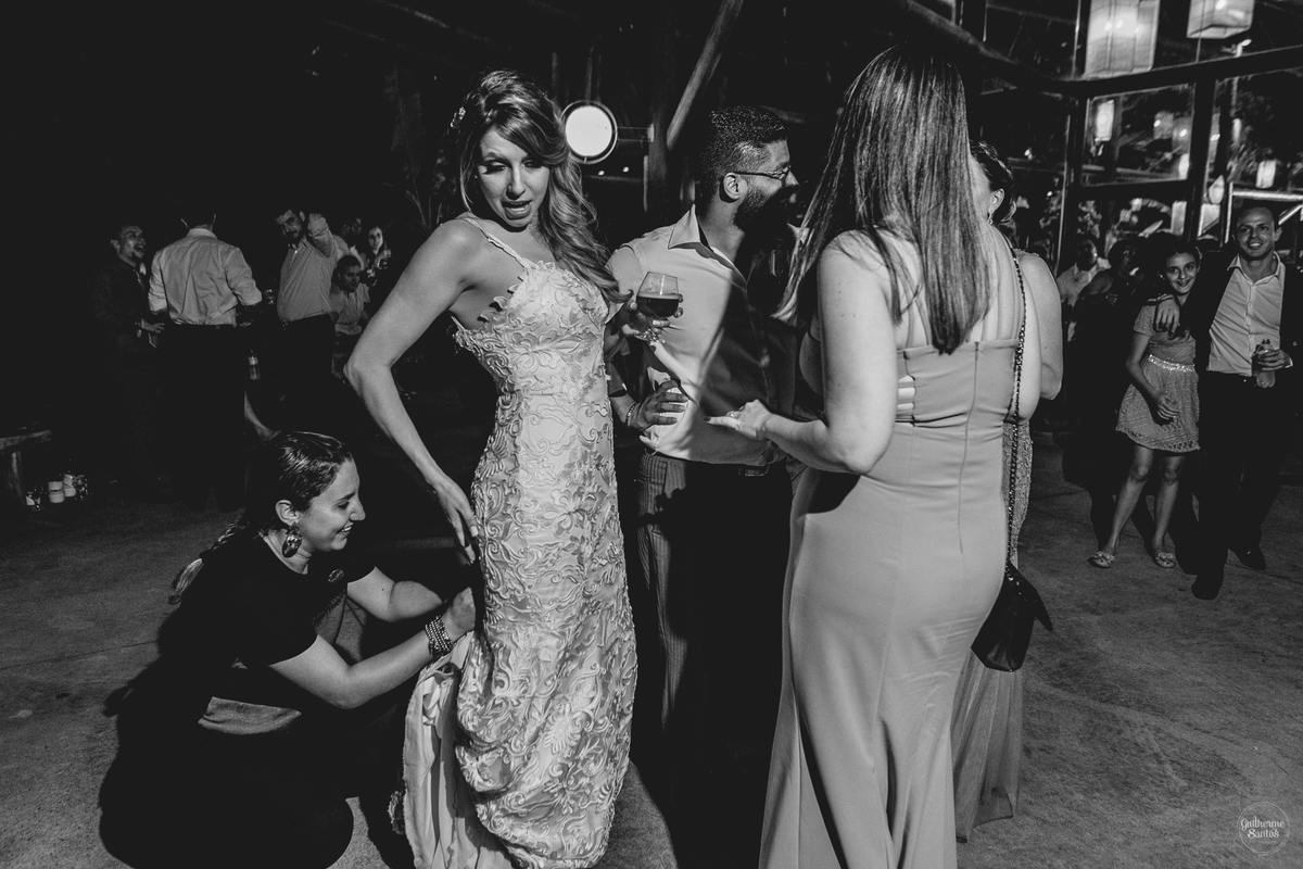 Fotografia de casamento pelo fotógrafo Guilherme Santos, cerimonialista ajudando a noiva com o vestido de noiva na festa de casamento em Botucatu.