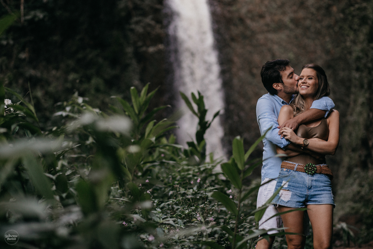 Fotografia de pré casamento feita no final de tarde pelo fotógrafo Guilherme Santos, casal de noivos estão se abraçando na sessão de fotos na cachoeira em Brotas.
