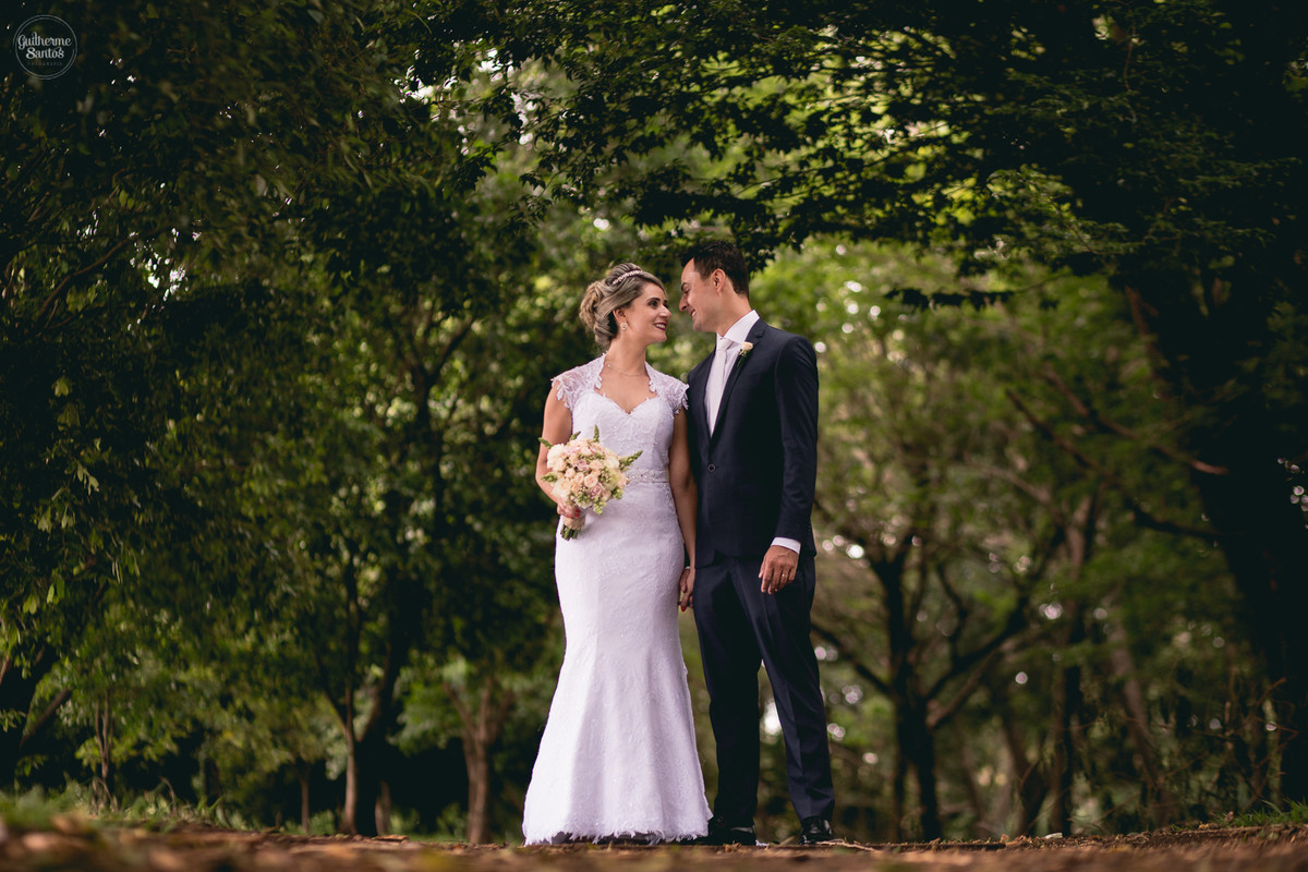 Fotografia de casamento pelo fotógrafo Guilherme Santos na região de Jaú Sp, Bauru Sp, sessão pos cerimonia noivos em um corredor de arvores se olhando e sorrindo.