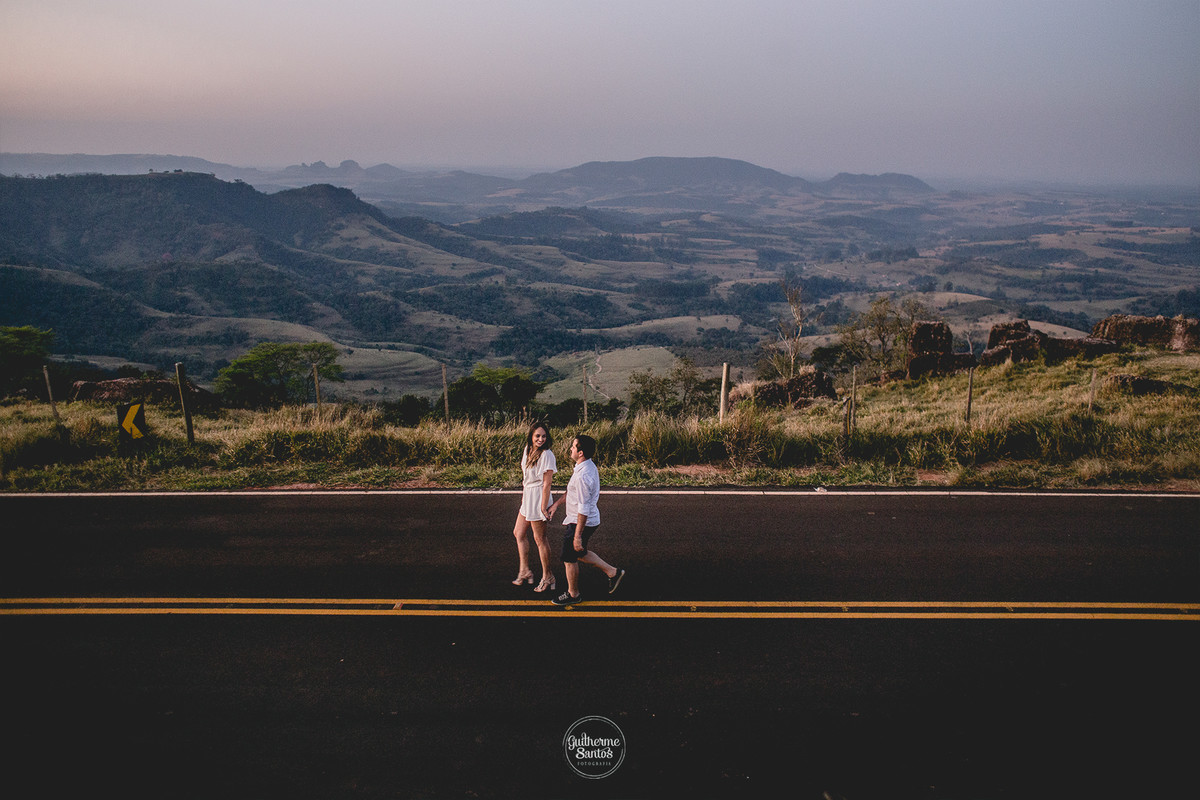 Fotografia de casamento pelo fotógrafo Guilherme Santos na região de Jaú Sp, Bauru Sp, noivos caminhando em estrada com vista para o gigante adormecido em botucatu sp.