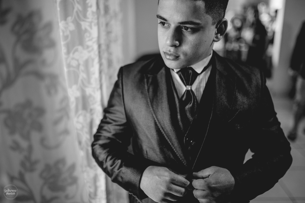 Fotografia de casamento pelo fotógrafo Guilherme Santos, noivo se arrumando em sua casa proximo a uma janela