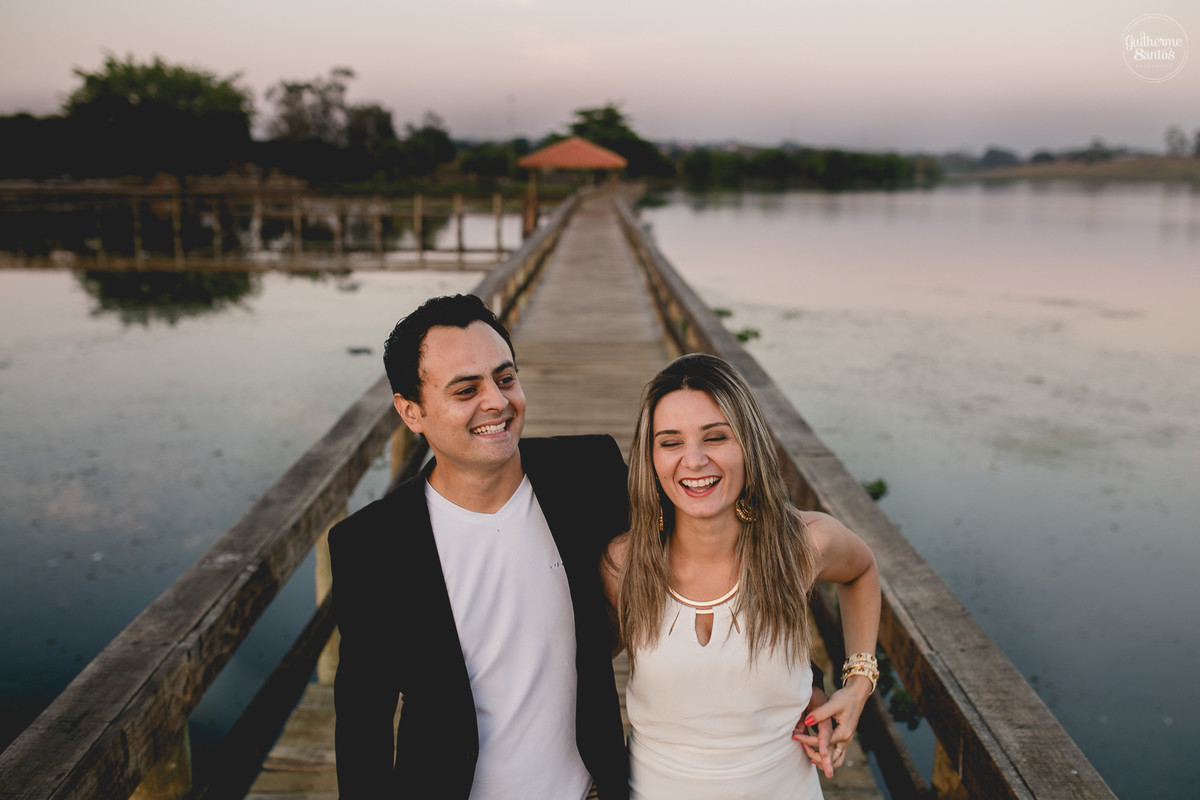 Ensaio pré casamento de Guilherme Santos Fotografia que rolou na Arealva – SP, sessão fotográfica no nascer do sol. Noivos sorrindo e caminhando em um deck proximo ao rio, uma paisagem linda.