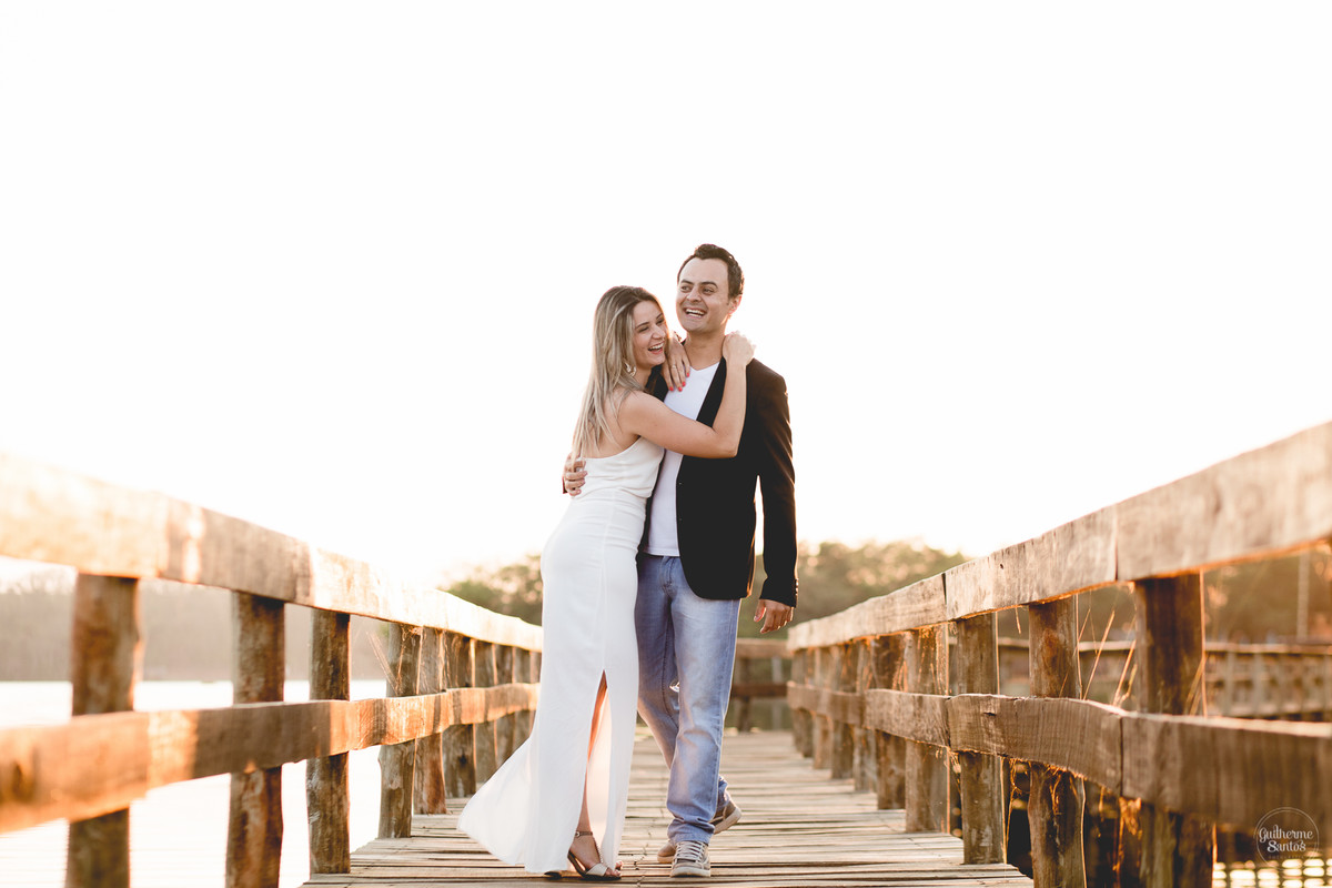 Ensaio pré casamento de Guilherme Santos Fotografia que rolou na Arealva – SP, sessão fotográfica no nascer do sol. Noivos se abraçando e sorrindo em um deck proximo ao rio, uma paisagem linda.