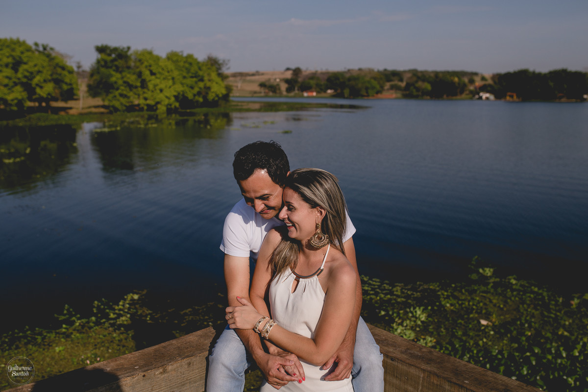 Ensaio pré casamento de Guilherme Santos Fotografia que rolou na Arealva – SP, sessão fotográfica no nascer do sol. Noivos se abraçando e sorrindo em um deck proximo ao rio, uma paisagem linda.
