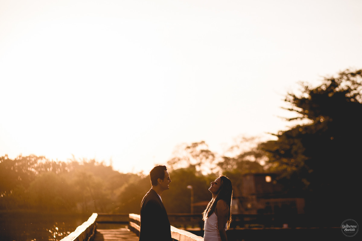 Ensaio pré casamento de Guilherme Santos Fotografia que rolou na Arealva – SP, sessão fotográfica no nascer do sol. Noivos se olhando e sorrindo em um deck proximo ao rio, uma paisagem linda.