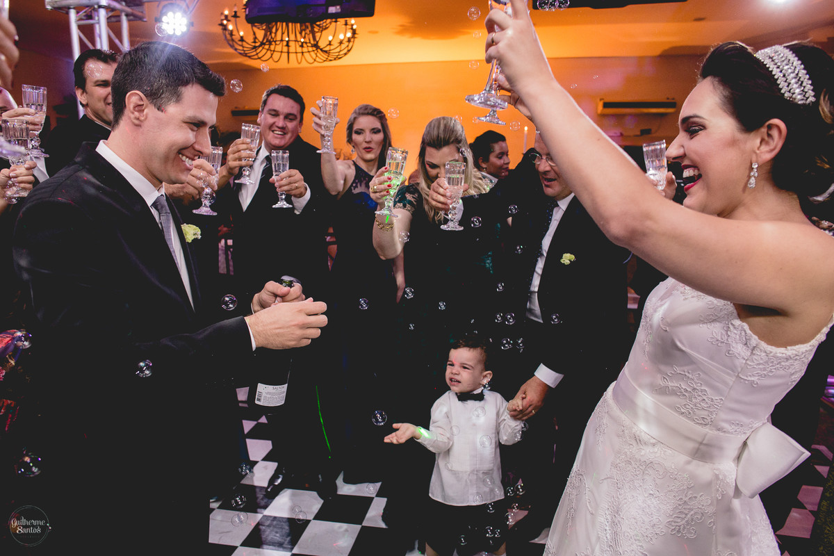 Fotografia de casamento pelo fotógrafo Guilherme Santos, brinde dos noivos junto com os convidados em festa de casamento