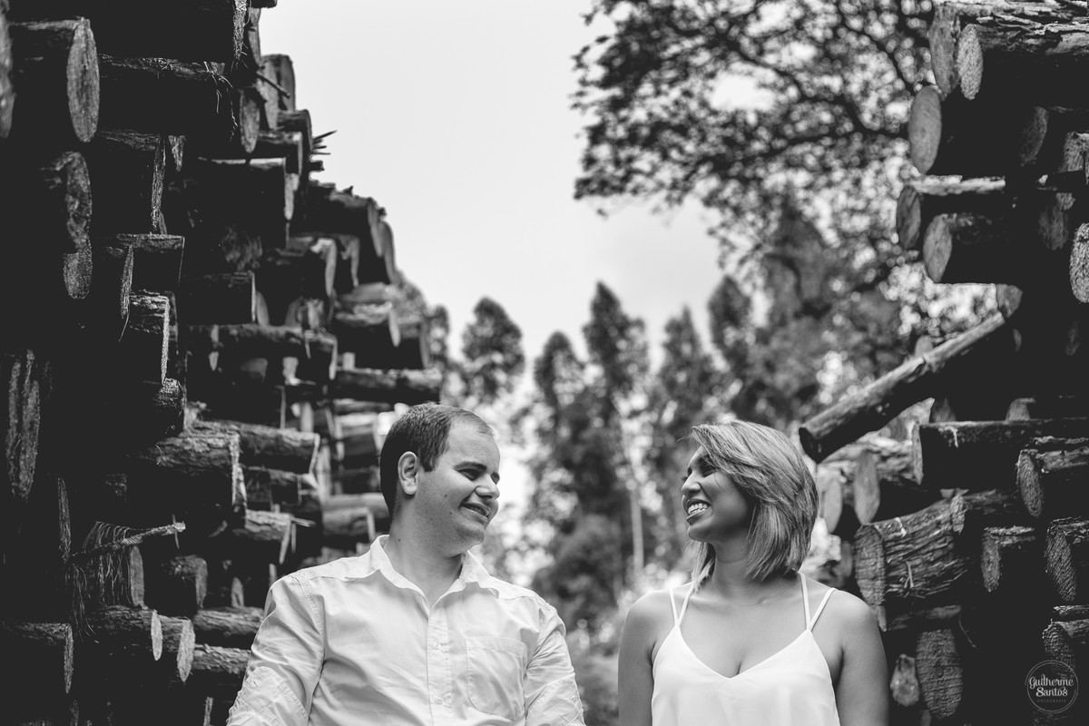 Ensaio pré casamento de Guilherme Santos Fotografia que rolou na Sengés-PR, sessão fotográfica no final de tarde. Noivos se olhando e sorrindo no meio de troncos de eucaliptos.