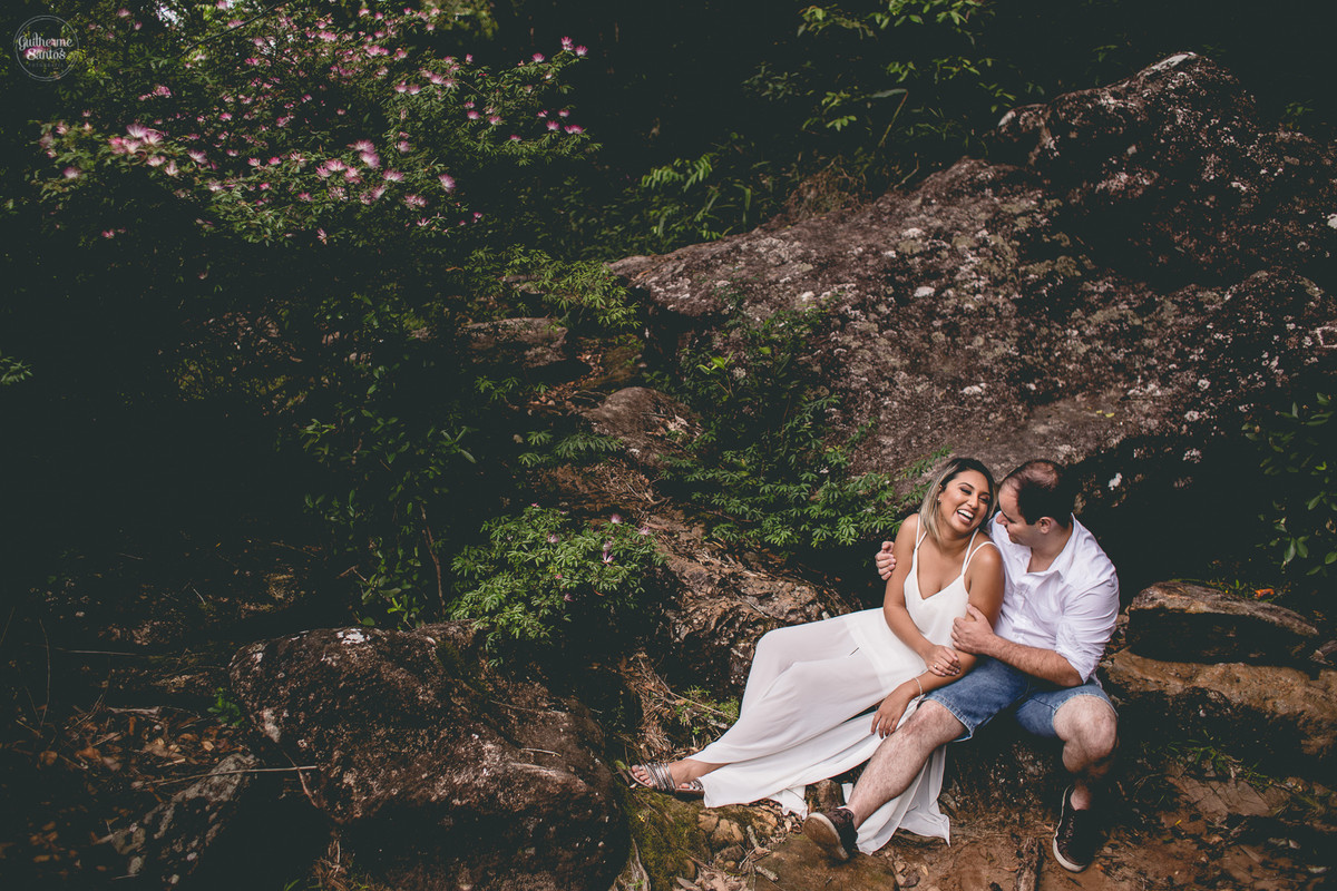 Ensaio pré casamento de Guilherme Santos Fotografia que rolou na Sengés-PR, sessão fotográfica no final de tarde. Noivos sentados e sorrindo em uma pedra juntos a uma paisagem linda.