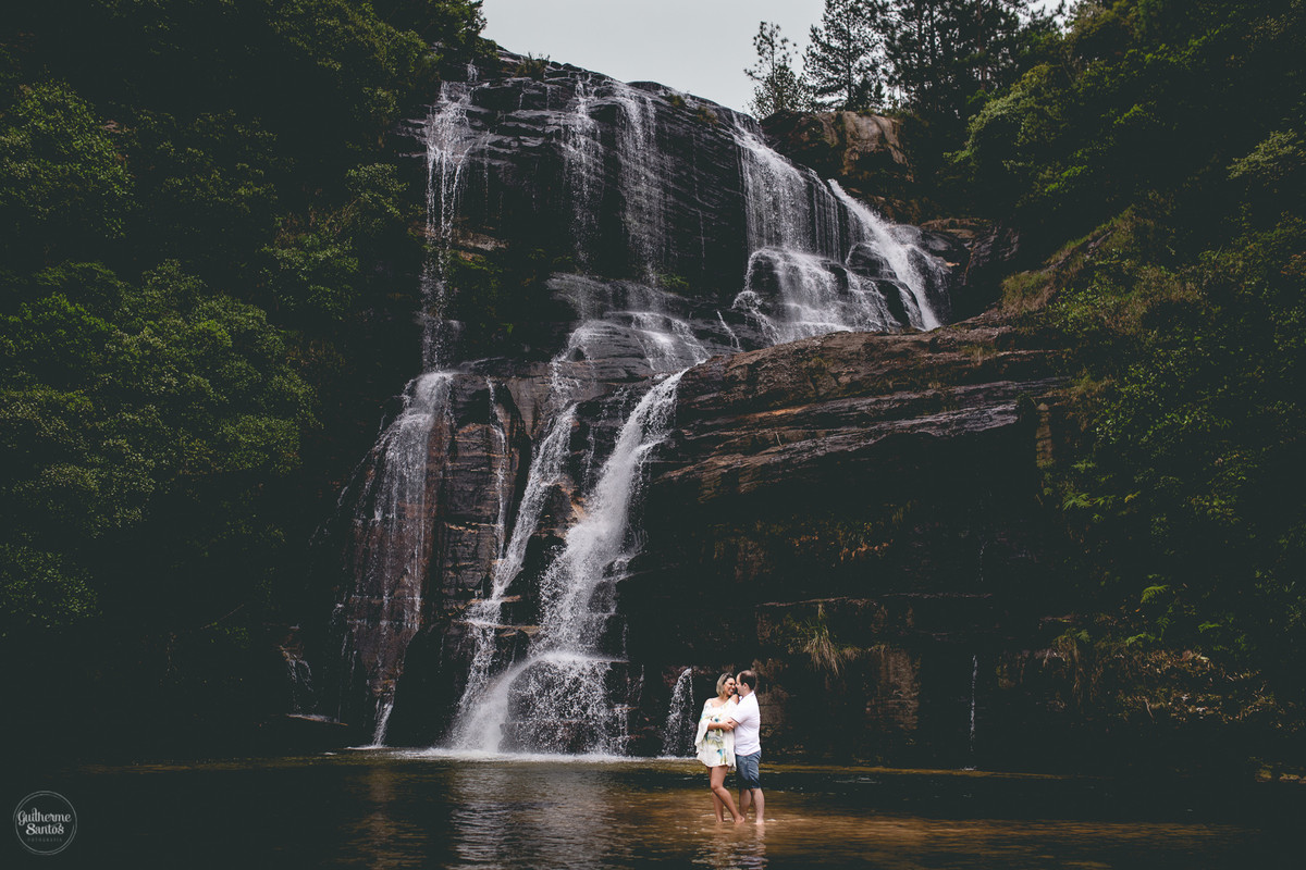 Ensaio pré casamento de Guilherme Santos Fotografia que rolou na Sengés-PR, sessão fotográfica no final de tarde. Noivos abraçados e sorrindo com a vista para uma cachoeira ao fundo.