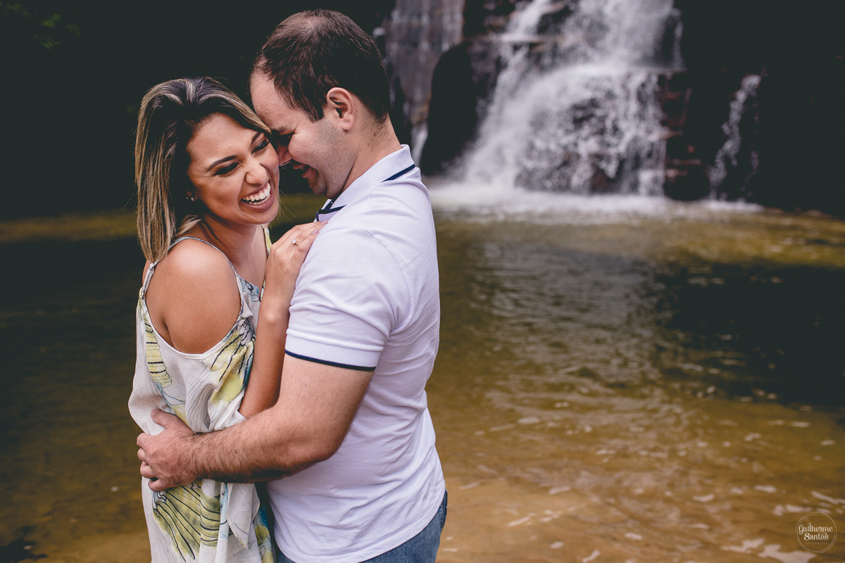 Ensaio pré casamento de Guilherme Santos Fotografia que rolou na Sengés-PR, sessão fotográfica no final de tarde. Noivos abraçados e sorrindo com a vista para uma cachoeira ao fundo.