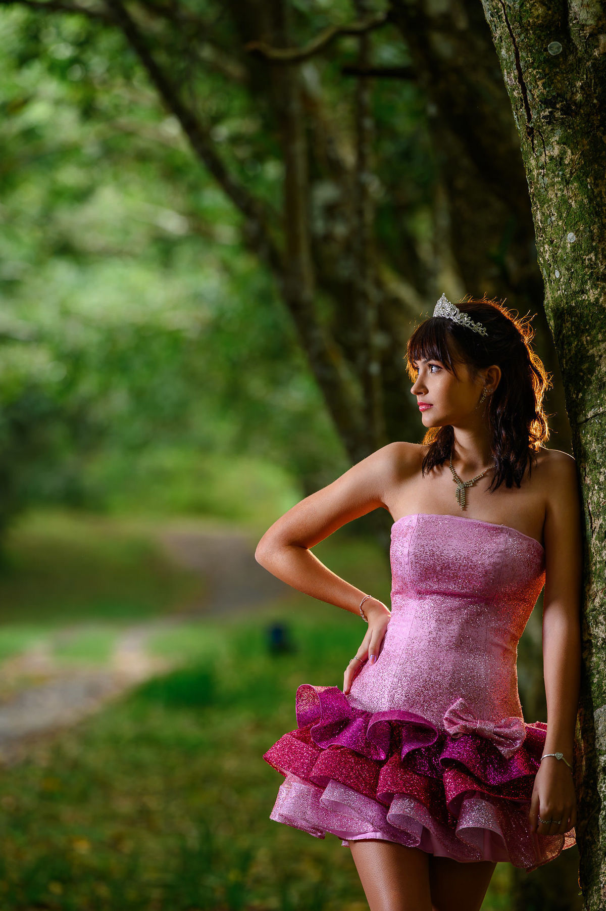 Ensaio de 15 anos em Balneário Camboriú com debutante em bosque, vestido rosa e coroa, em cenário natural