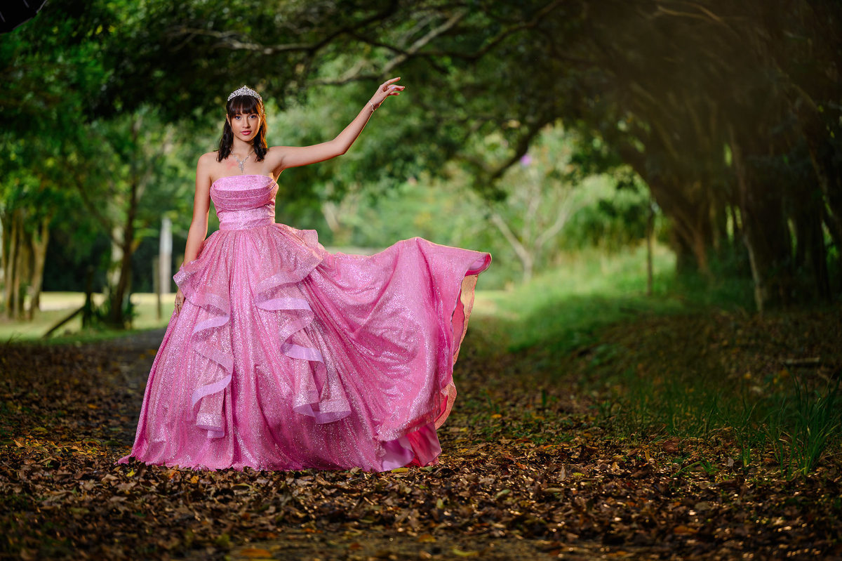 Ensaio fotográfico de 15 anos em Balneário Camboriú com debutante em vestido longo rosa em meio à natureza