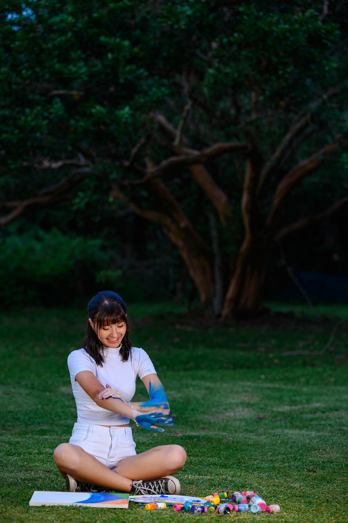 Ensaio fotográfico de 15 anos em Balneário Camboriú SC com debutante brincando com tintas coloridas em cenário natural