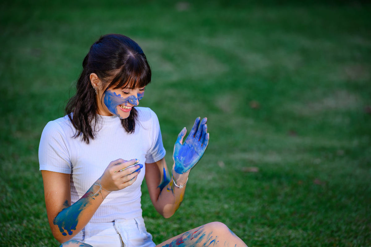 Retrato de debutante de 15 anos com tinta no rosto em ensaio fotográfico artístico em bosque de Balneário Camboriú SC