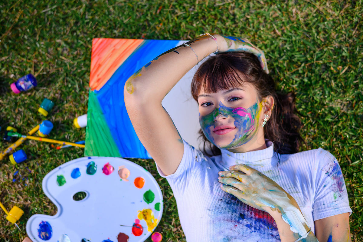 Ensaio de 15 anos em Balneário Camboriú SC com fotografia criativa de debutante segurando paleta de pintura ao ar livre