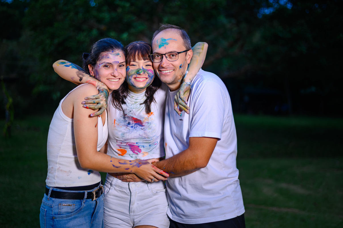 Ensaio fotográfico de 15 anos em Balneário Camboriú SC com retrato da debutante junto dos pais em momento espontâneo no bosque