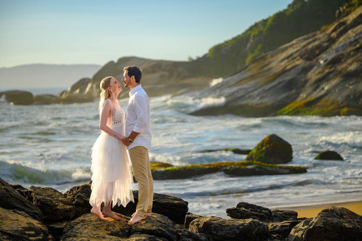 Fotografia de casal com luz de amanhecer e mar ao fundo