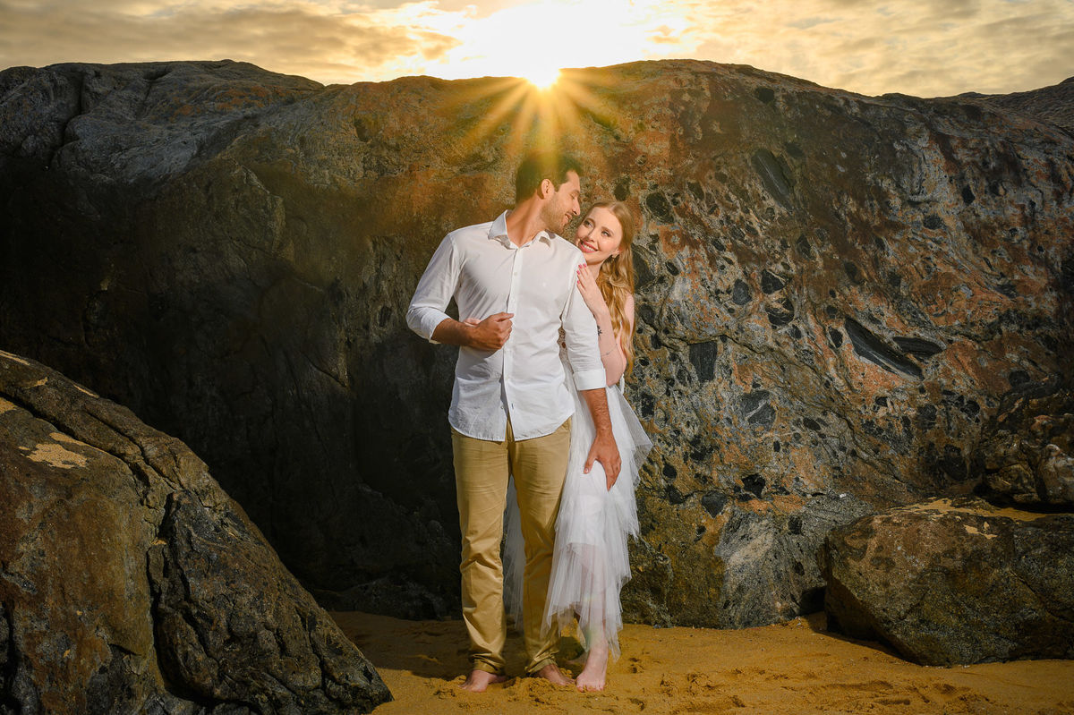 Fotografia de casal com luz de amanhecer e mar ao fundo