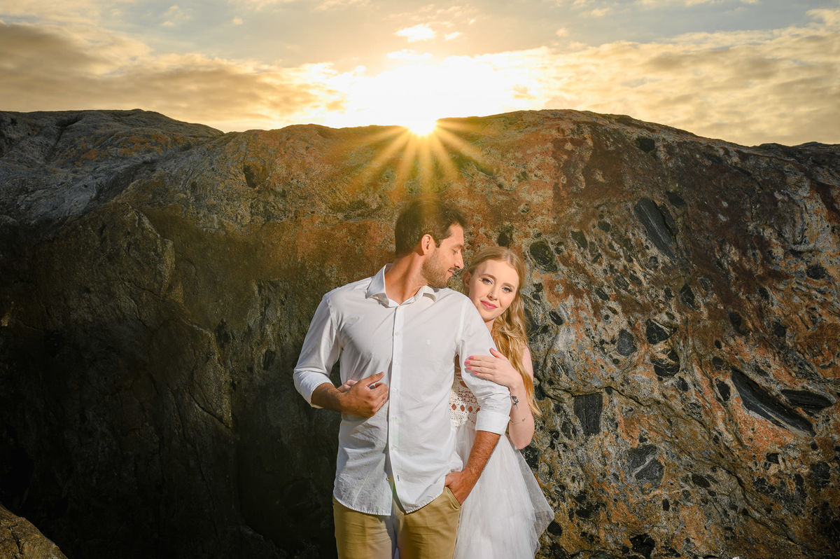 Fotografia de casal com luz de amanhecer e mar ao fundo