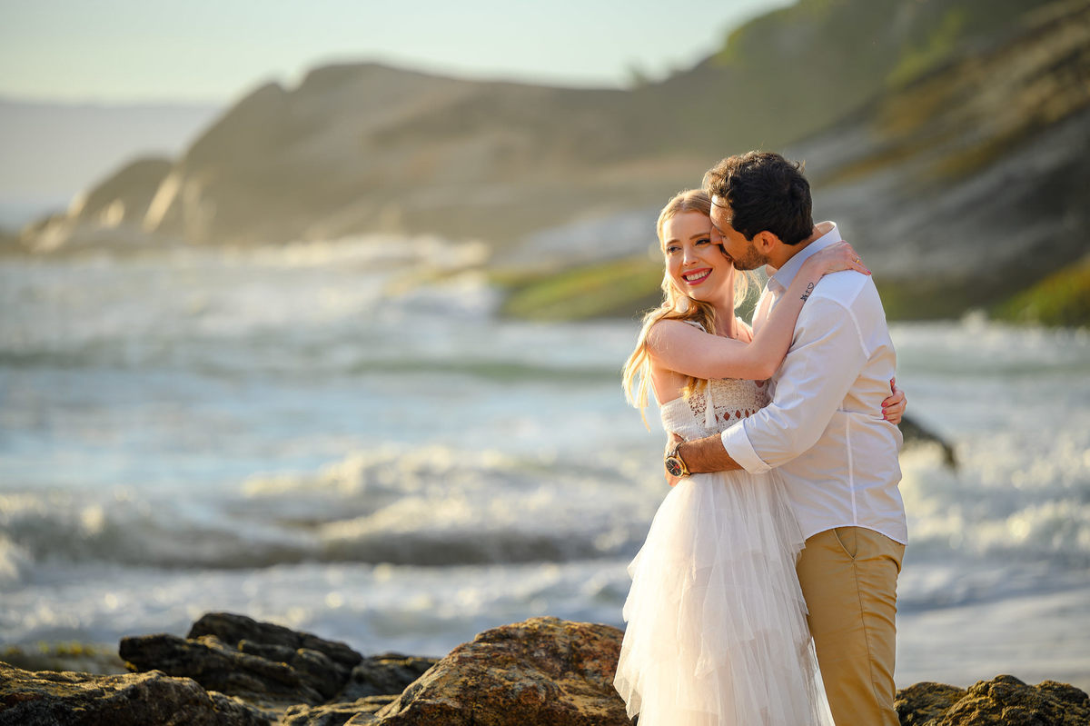 Fotografia de casal com luz de amanhecer e mar ao fundo