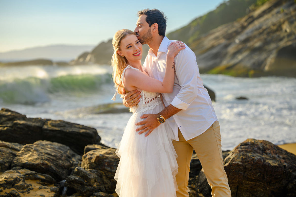 Fotografia de casal com luz de amanhecer e mar ao fundo
