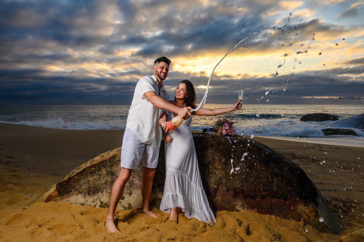casal comemorando com espumante durante ensaio pré wedding na praia em Balneário Camboriú