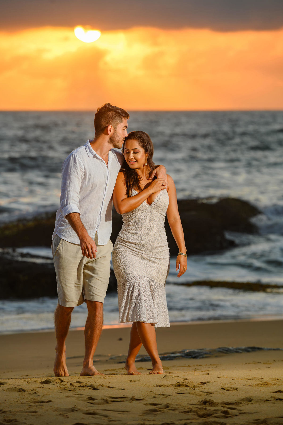 Casal caminhando de mãos dadas na Praia do Estaleirinho ao nascer do sol