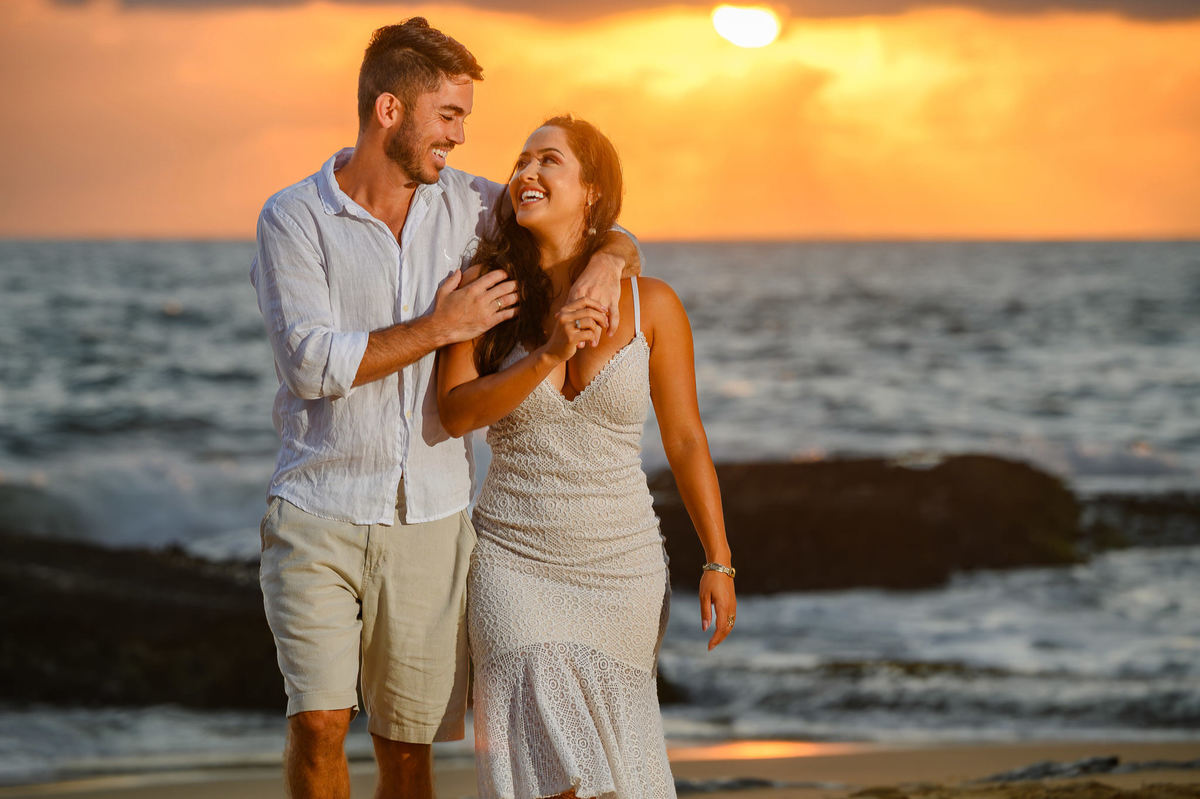 Casal caminhando de mãos dadas na Praia do Estaleirinho ao nascer do sol