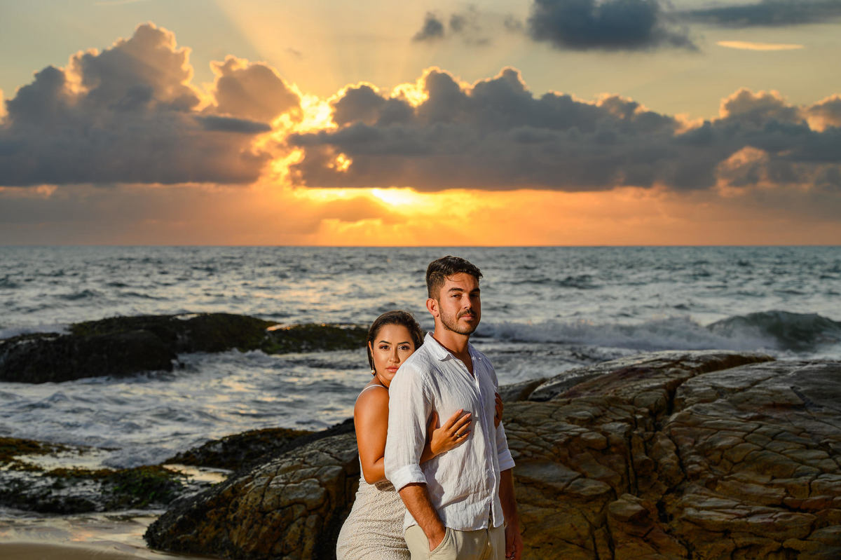 Ensaio de casal na praia com o sol surgindo no horizonte em Balneário Camboriú