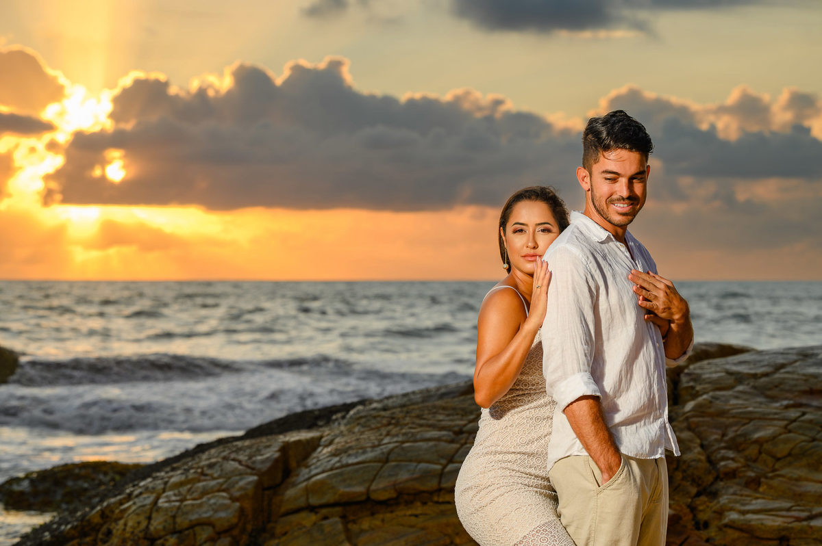 Ensaio de casal na praia com o sol surgindo no horizonte em Balneário Camboriú