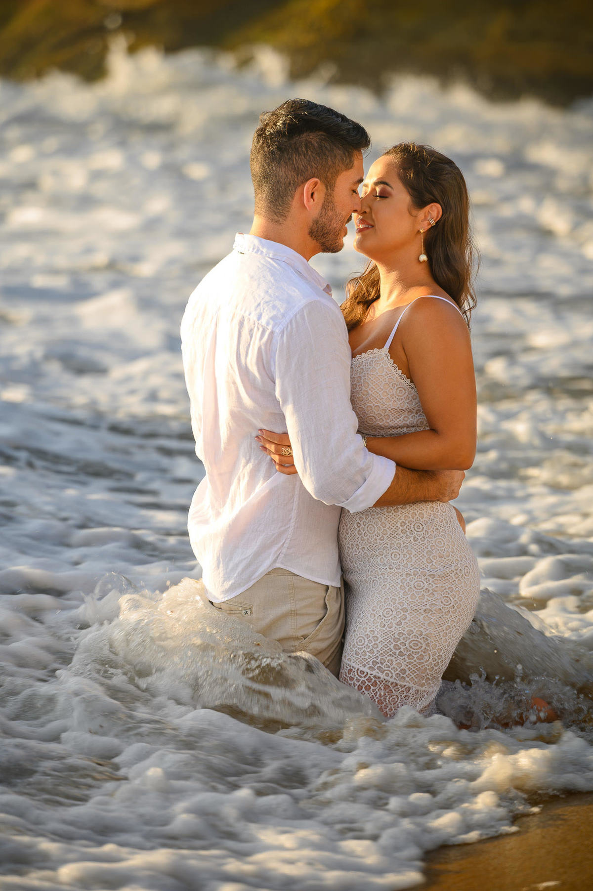 casal ajoelhado no mar durante ensaio fotográfico em Balneário Camboriú, SC