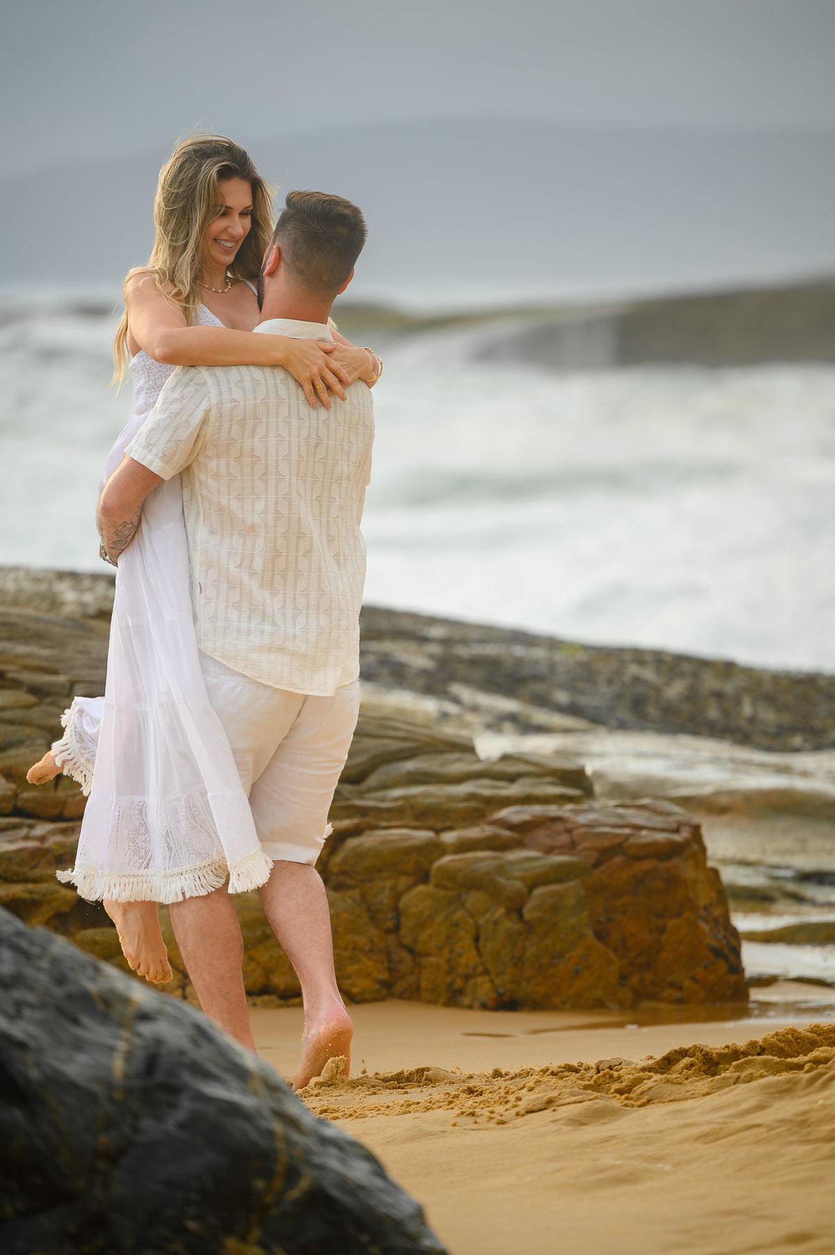 Ensaio pré-wedding com casal abraçado nas pedras da Praia do Estaleirinho
