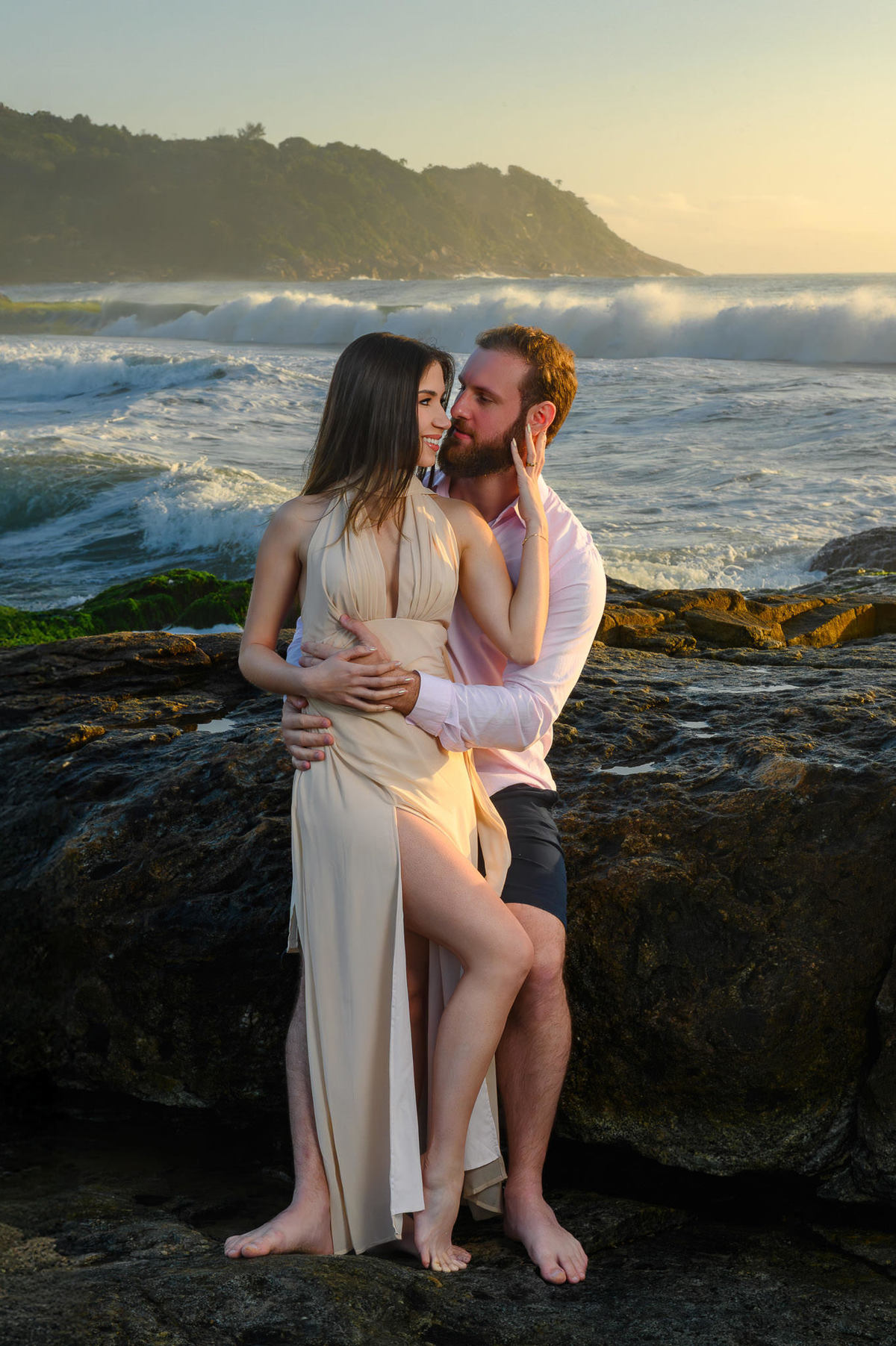 Ensaio pré-wedding com casal sentado nas pedras e ondas do mar em Balneário Camboriú